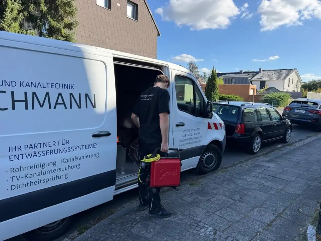 Techniker von Rohrfachmann mit Prüfkoffer am Servicefahrzeug